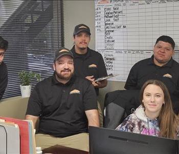 photo of female employee sitting at a desk with crew around