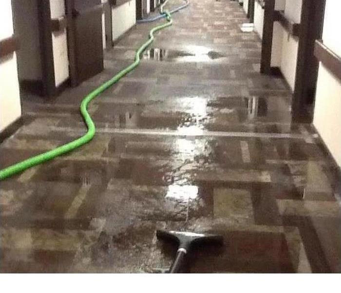 Water damage equipment set up to remove the standing water in a commercial building hallway