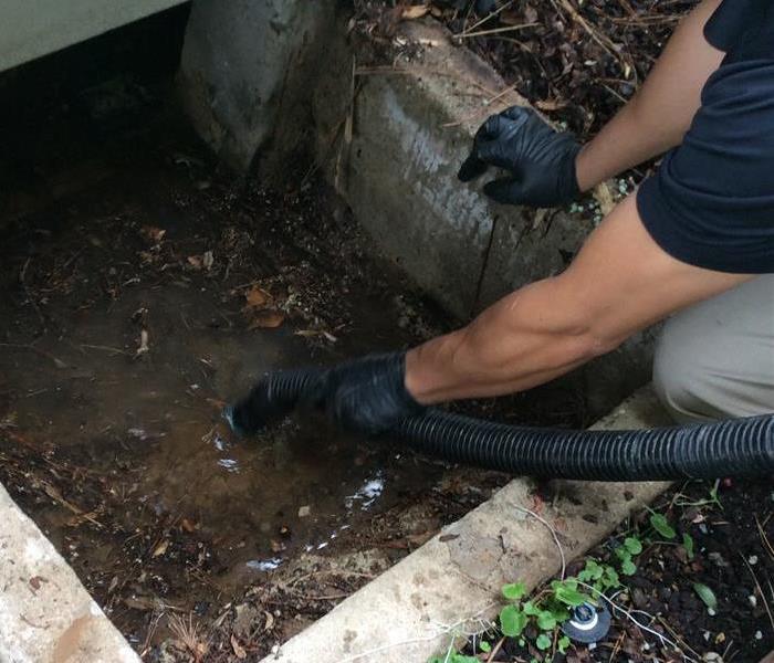 SERVPRO employee removing water from under a house