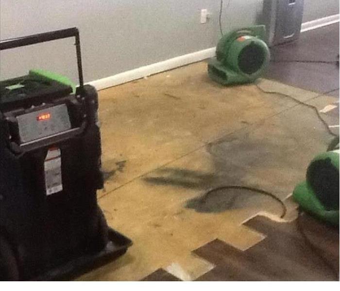 Drying equipment placed around a partially removed wood flooring from a water damaged building
